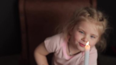 A small child makes a wish while looking at a candle. Dreams Come True