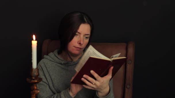 Femeie Citește Carte Lumânare Arde Lângă Femeia Este Interesată Citească — Videoclip de stoc