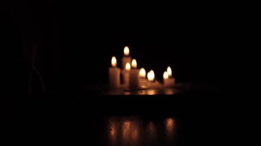 A few candles glow in the dark. Burning candles on a black background. Yellow candles. The flame burns out