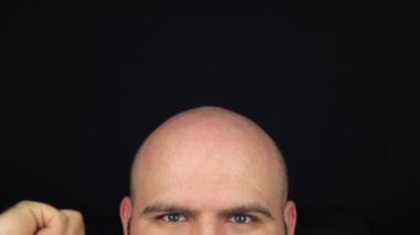 The bald man takes a comb and combs his head. Combing his bald head, A man without hair