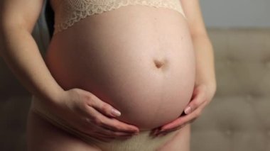 Pregnant woman in underwear. She is 30 weeks pregnant and has a big belly. Expecting a child. Third pregnancy