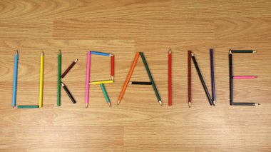 Colored pencils on a wooden background. Preparation for school, drawing lesson. The word Ukraine is made up of pencils.