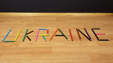 Colored pencils on a wooden background. Preparation for school, drawing lesson. The word Ukraine is made up of pencils.