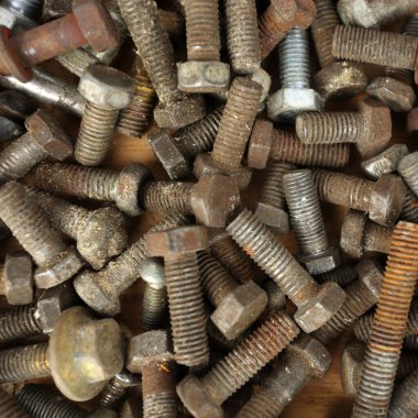 Many rusty elements. Old rusty bolt. Dirty metal bolts are scattered on the table. Old spare parts warehouse