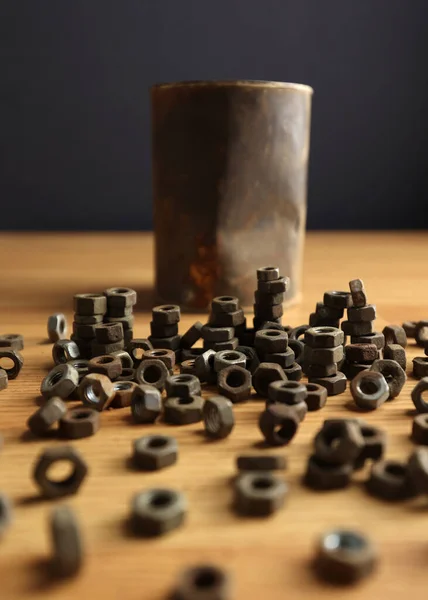 Many rusty elements. Old rusty nut. Dirty metal nuts are scattered on the table. Old spare parts warehouse