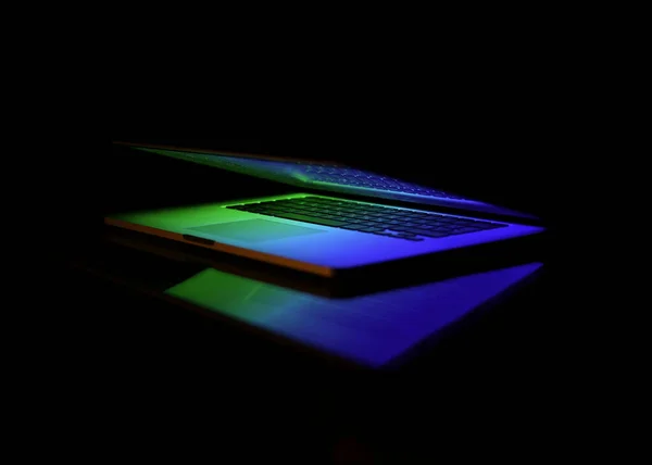 Laptop on a black background. Slightly open laptop. The computer screen lights up, the keyboard lights up