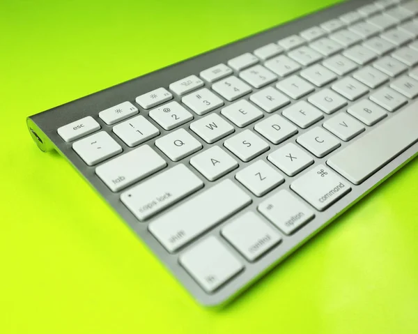 Gray keyboard with white buttons. Wireless keyboard. Computer components. Text input device. Keyboard on a yellow-green background