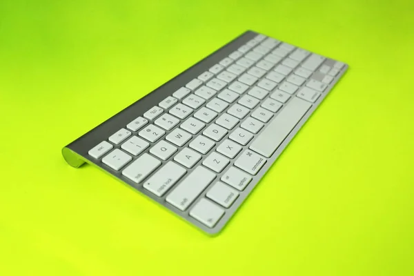 Gray keyboard with white buttons. Wireless keyboard. Computer components. Text input device. Keyboard on a yellow-green background