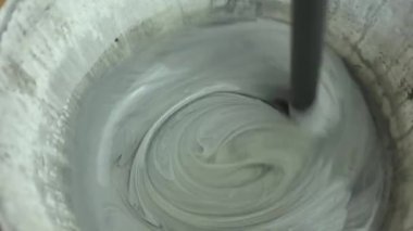 Kovadaki gri boyayı karıştırır. Boya burada işe yarıyor. Daireyi toparlıyorum. Binanın tamiri. Kötü karıştırılmış boya. Yakından.