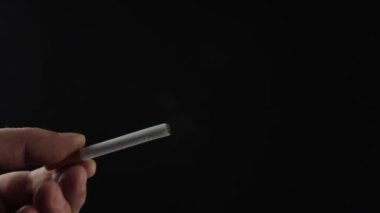 Bir adam sigara içiyor. Sigara içmeyi arzuluyorum. Siyah arka planda bir sigara, duman görünür. Bir sürü zararlı duman. Tecrübeli bir sigara tiryakisi. Bu sağlığın için kötü. Sorunlar ve depresyon