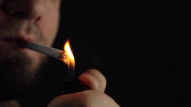 Bir adam sigara içiyor. Sigara içmeyi arzuluyorum. Siyah arka planda bir sigara, duman görünür. Bir sürü zararlı duman. Tecrübeli bir sigara tiryakisi. Bu sağlığın için kötü. Sorunlar ve depresyon