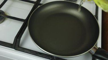 Yemek pişirmek. Tavada yağda kızartma. Beyaz soba, kahvaltı hazırlamak. Siyah kızartma tavası. Tavada çok fazla yağ var..