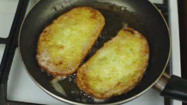 Yumurtada ekmek pişirmek. Tavada yağda kızartma. Beyaz soba, kahvaltı hazırlamak. Siyah kızartma tavası. Tavada çok fazla yağ var. Yağlı yemek, bol kolesterol. Kahvaltıda kızarmış ekmek.