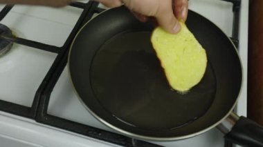 Yumurtada ekmek pişirmek. Tavada yağda kızartma. Beyaz soba, kahvaltı hazırlamak. Siyah kızartma tavası. Tavada çok fazla yağ var. Yağlı yemek, bol kolesterol. Kahvaltıda kızarmış ekmek.