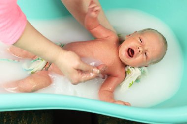 Yeni doğmuş bir bebek. Yeni doğmuş erkek bebek suda yüzüyor. İki haftalık bir bebeğin hayatının ilk günleriydi. Beyaz saçlı bir çocuk. Ebeveynler için sevinç, yeni doğmuş bir çocuk. Çocuk prosedürleri. Küçük banyo.