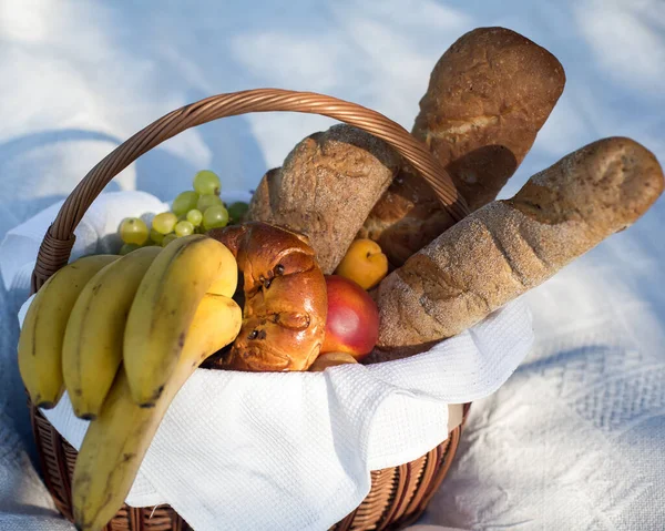 Outdoor recreation. Picnic in the garden. A wooden basket with fruit and a baguette. Recreation in the fresh air.