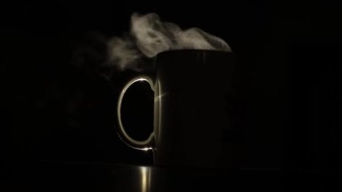 Arkadan gelen ışıkla aydınlatılmış, siyah arka planda bir fincan kahve. Geceleri siluetli, kahve bariz bir şekilde görülebiliyor. Espresso yapıyorum, mola zamanı..
