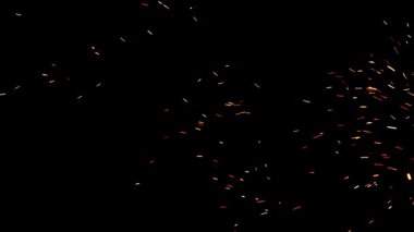 Şenlik ateşinden çıkan alevler. Siyah arkaplandaki ateş kıvılcımları geçiş için bir kaplama olarak kullanılabilir. Doğal bir kıvılcım. Havada yanıcı parçacıklar var. Çeşitli projelerde kullanmak için