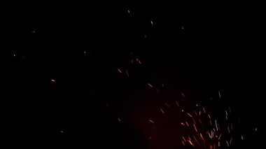 Şenlik ateşinden çıkan alevler. Siyah arkaplandaki ateş kıvılcımları geçiş için bir kaplama olarak kullanılabilir. Doğal bir kıvılcım. Havada yanıcı parçacıklar var. Çeşitli projelerde kullanmak için