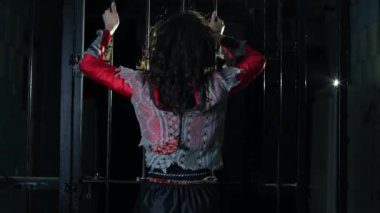 Cadılar Bayramı tarzında esmer bir kız. Hapisteki bir kadın, korkunç bir sahne. Korkunç bir karanlık, kızın üzerinde yırtık giysiler. Kafesteki rehine, depresyon, acı çekme, suç. Kara Karnaval, bodrumda..