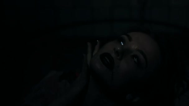 ハロウィーンスタイルのブルネットガール 黒い背景の女性 彼女の顔に明るい光 怖いシーン 恐ろしい闇 うつ病 苦しみ ブラックカーニバル 地下室 — ストック動画