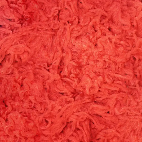 A lot of tangled thread. Red fabric background. Cords for knitting clothes, sewing factory. Soft threads for sewing. Red fluffy background. Thread for weaving.