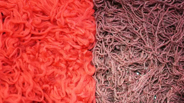A lot of tangled thread. Red fabric background. Cords for knitting clothes, sewing factory. Soft threads for sewing. Red fluffy background. Thread for weaving.