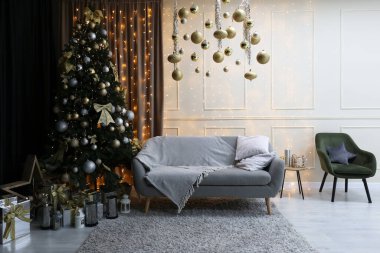 Şenlikli bir yeni yıl odasının içi. Noel atmosferi, kanepe ve Noel ağacı, beyaz duvarlar. Evde mutlu yıllar. Güzel daire, modern bina.