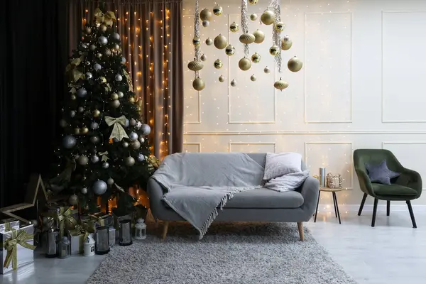 Interior of a festive New Year\'s room. Christmas atmosphere, sofa and Christmas tree, white walls. Happy New Year at home. Nice apartment, modern premises