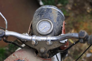 Eski motosiklet toz içinde. Kırmızı retro moto. Arızalı motosiklet, tamire ihtiyacı var. Kirli bir kırsal benzinli motosiklet, hemen yanındaki çöplükte.