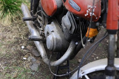 Eski motosiklet toz içinde. Kırmızı retro moto. Arızalı motosiklet, tamire ihtiyacı var. Kirli bir kırsal benzinli motosiklet, hemen yanındaki çöplükte.