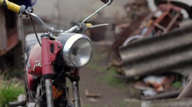 Eski motosiklet toz içinde. Kırmızı retro moto. Arızalı motosiklet, tamire ihtiyacı var. Kirli bir kırsal benzinli motosiklet, hemen yanındaki çöplükte.