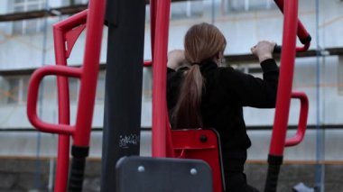 Avluda simülatör eğitimi. Kız kilo veriyor, motivasyonu var. Spor sahası, siyah eşofmanlı bir kadın egzersiz yapıyor. Açık hava sporları, sağlıklı yaşam tarzı.