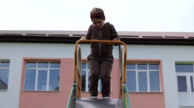 Küçük bir kız çocuk parkında oynuyor. Halka açık bir yerde eğlence. Çocuk temiz havada dinleniyor. Çocukların kaydırağından iniyor.