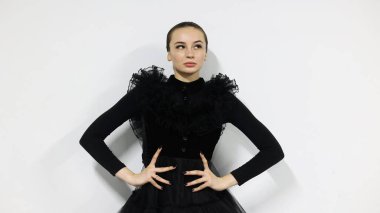 Beyaz arka planda balerin, siyah bir elbise giyiyor. Esmer bir kız kameranın önünde poz veriyor. Güzel dansçı, siyah beyaz stili..