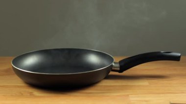 Tava masanın üzerinde siyah. Kızartma tavası, kızartma için yağ içeren mutfak malzemesi. Evde kahvaltı hazırlıyorum..