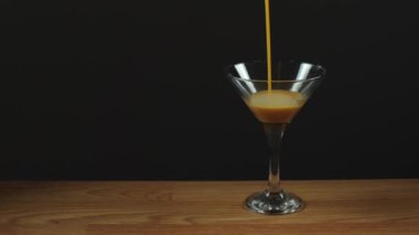 Likör martini bardağına dökülür. Tarçın renkli alkolik içeceği. Alkolizm, barda sarhoşluk. Tatlı içeceğin az miktarda alkol içeriyor.