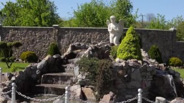 Temiz su akıntısı. Küçük bir şelale, temiz ve soğuk bir su kaynağı. Parkta su, güzel bir melek. Haç Yolu Dekorasyonları