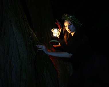 Karanlık bir ormanda, siyah elbiseli bir cadı. Cadının kafasında çelenk var. Güzel bir genç kız uykulu giyiniyor, bir ritüel gerçekleştiriyor ve büyü yapıyor.