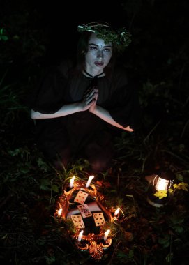 Karanlık bir ormanda, siyah elbiseli bir cadı. Cadının kafasında çelenk var. Güzel bir genç kız uykulu giyiniyor, bir ritüel gerçekleştiriyor ve büyü yapıyor.