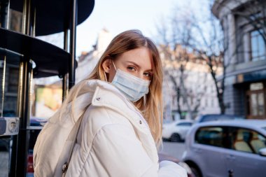  Beautiful girl in a medical mask. Protection from coronavirus on the street in pandemic. 