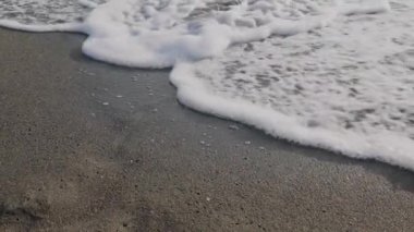 Kara kum üzerinde deniz dalgaları ve köpük. Kumsal ve rahatlama. Yüksek kalite 4k görüntü