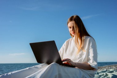 Kumsalda dizüstü bilgisayarı olan bir kız çalışıyor. Serbest programcı. Emlakçı. Yüksek kalite fotoğraf