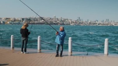 29.04.2024, İstanbul, Türkiye - Bir balıkçı halatını denize atıyor ve bir balık yakalıyor. Yüksek kalite 4k görüntü