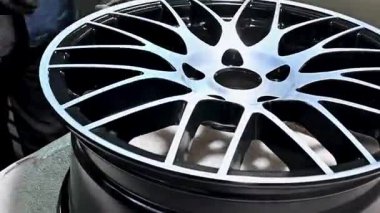 Yetenekli teknisyen, parlak atölye ışıkları altında özel araba tekerleğini titizlikle cilalıyor, kaliteli işçilik ve otomotiv geliştirme detaylarına dikkat çekiyor.