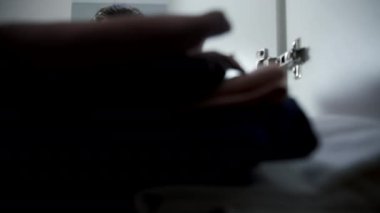 Genç adam tüm giysileri seçer ve dolaptan alır, yakından bakar. Gardırop kapısını açıp kapatıyor, dolabın içinden ateş ediyor. Şehir dairesinde günlük yaşam ve rutin.