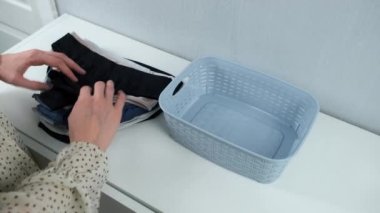 Kadınların elleri külotu düzgünce katlıyor ve konteynırın içine koyuyor, yakın çekim görüntüsü. Eşyaları ve giysileri evde depolamanın bir yolu..