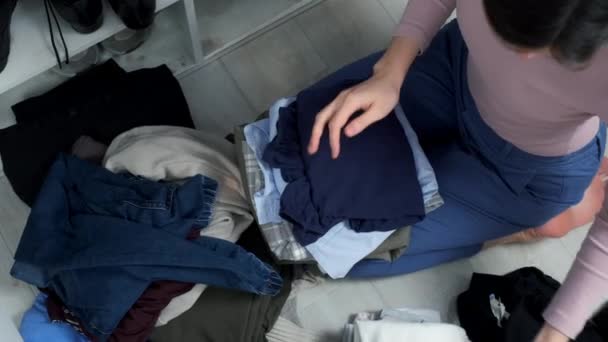 Kadın Elbiselerini Düzgünce Katlayarak Dolabını Düzenliyor Yerde Oturuyor Elbiselerini Düzenliyor — Stok video