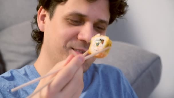 Porträt Eines Lächelnden Jungen Mannes Isst Sushi Rollen Wohnzimmer Mit — Stockvideo