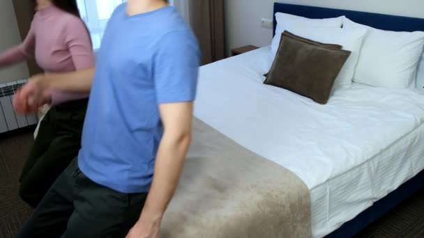 Junges Glückliches Paar Urlaub Springt Hotelzimmer Aufs Bett Seitenansicht Zeitlupe — Stockvideo